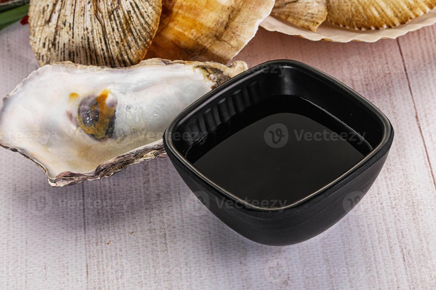 A bowl of black liquid next to an oyster photo