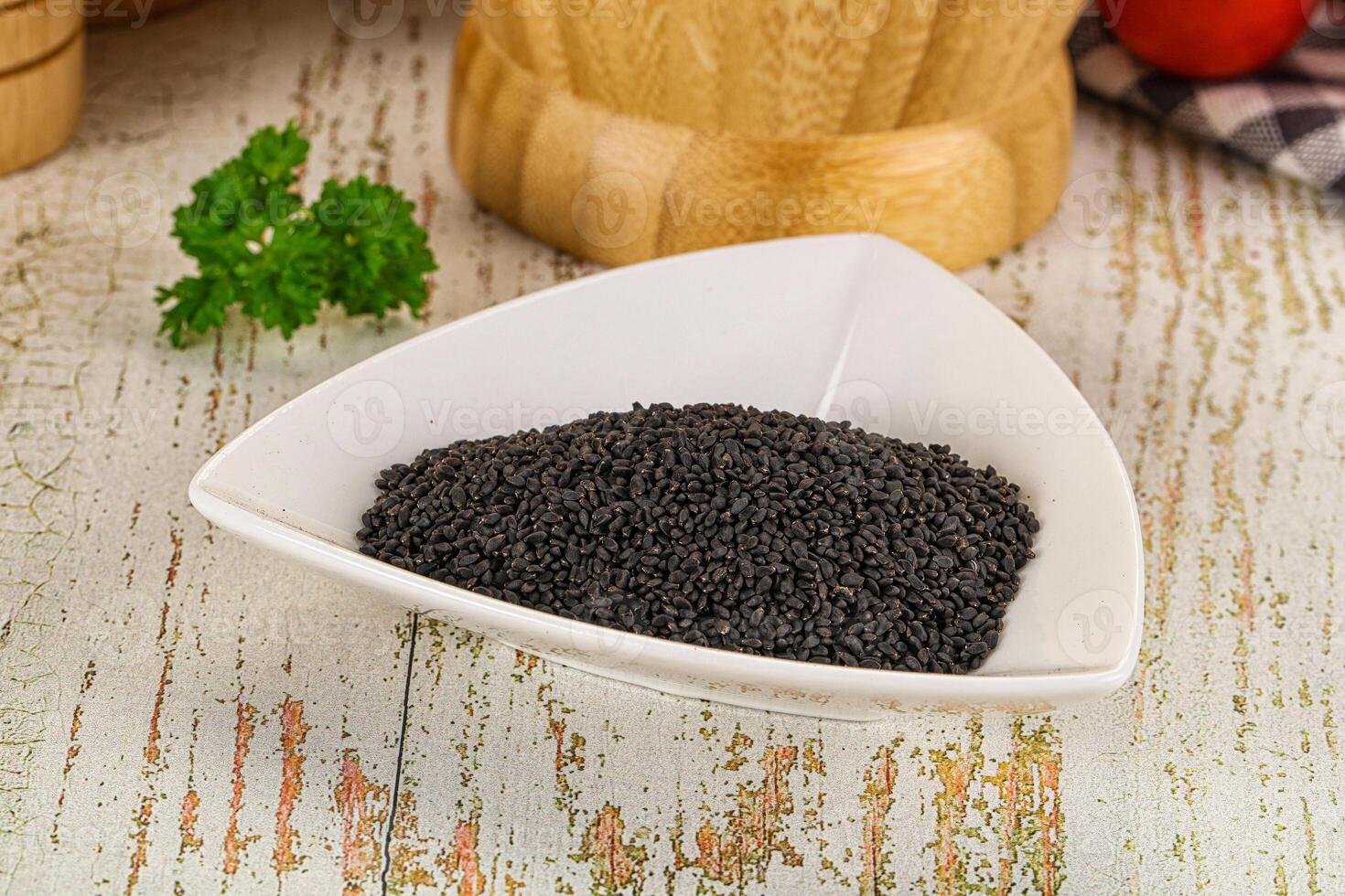 A bowl of black seeds on a table next to a knife photo