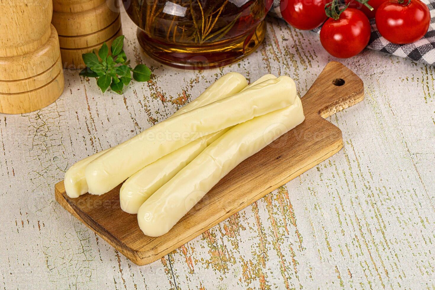 A wooden cutting board with cheese sticks on it photo