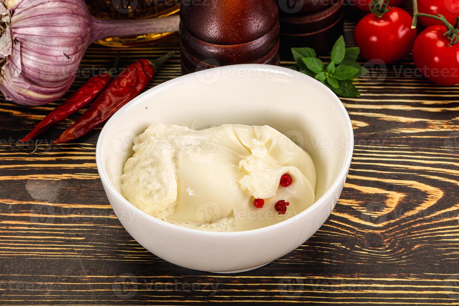 A bowl of ice cream sitting on a table next to a bowl of tomatoes and garlic photo