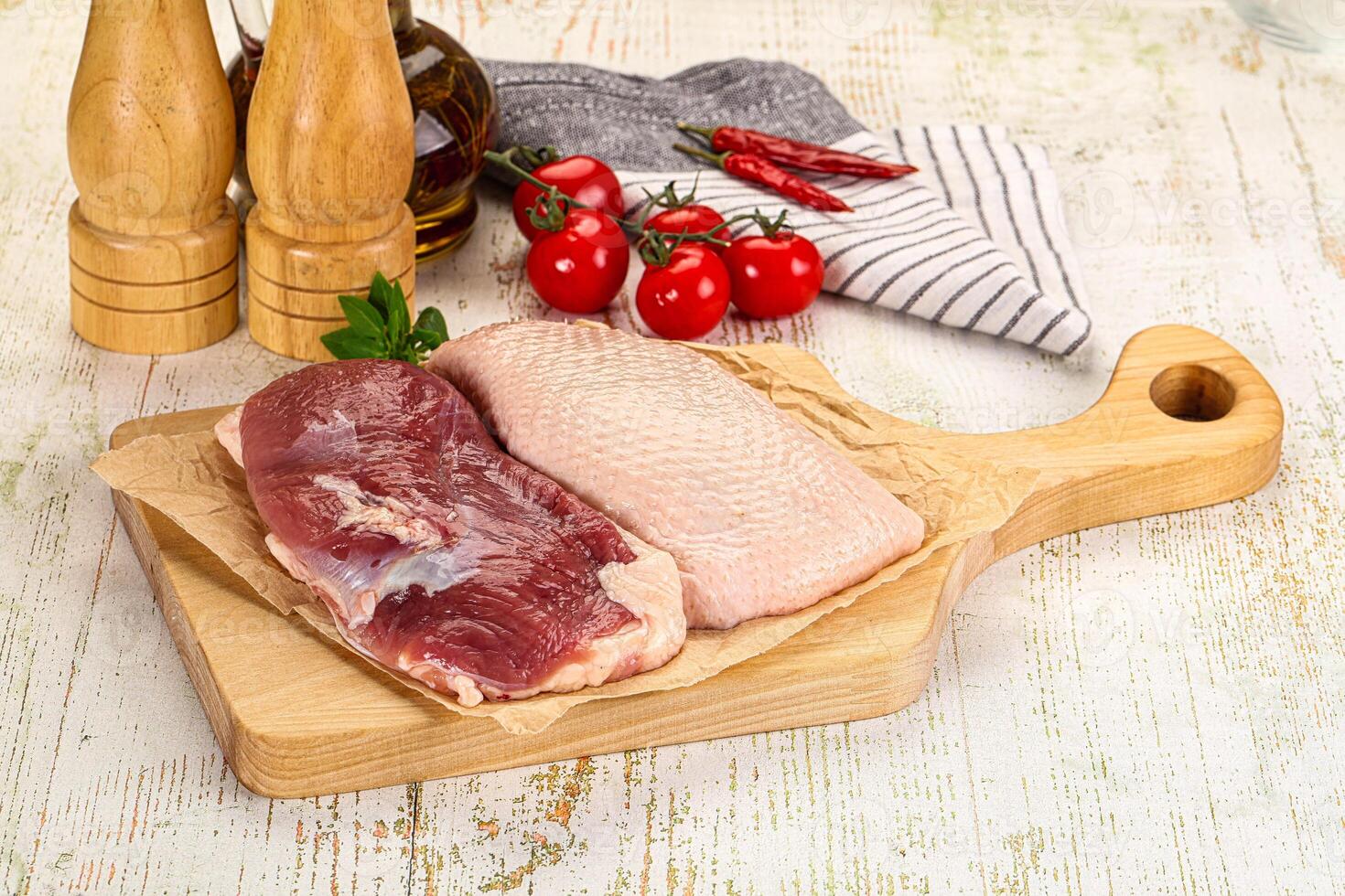 A wooden cutting board with meat and vegetables on it photo
