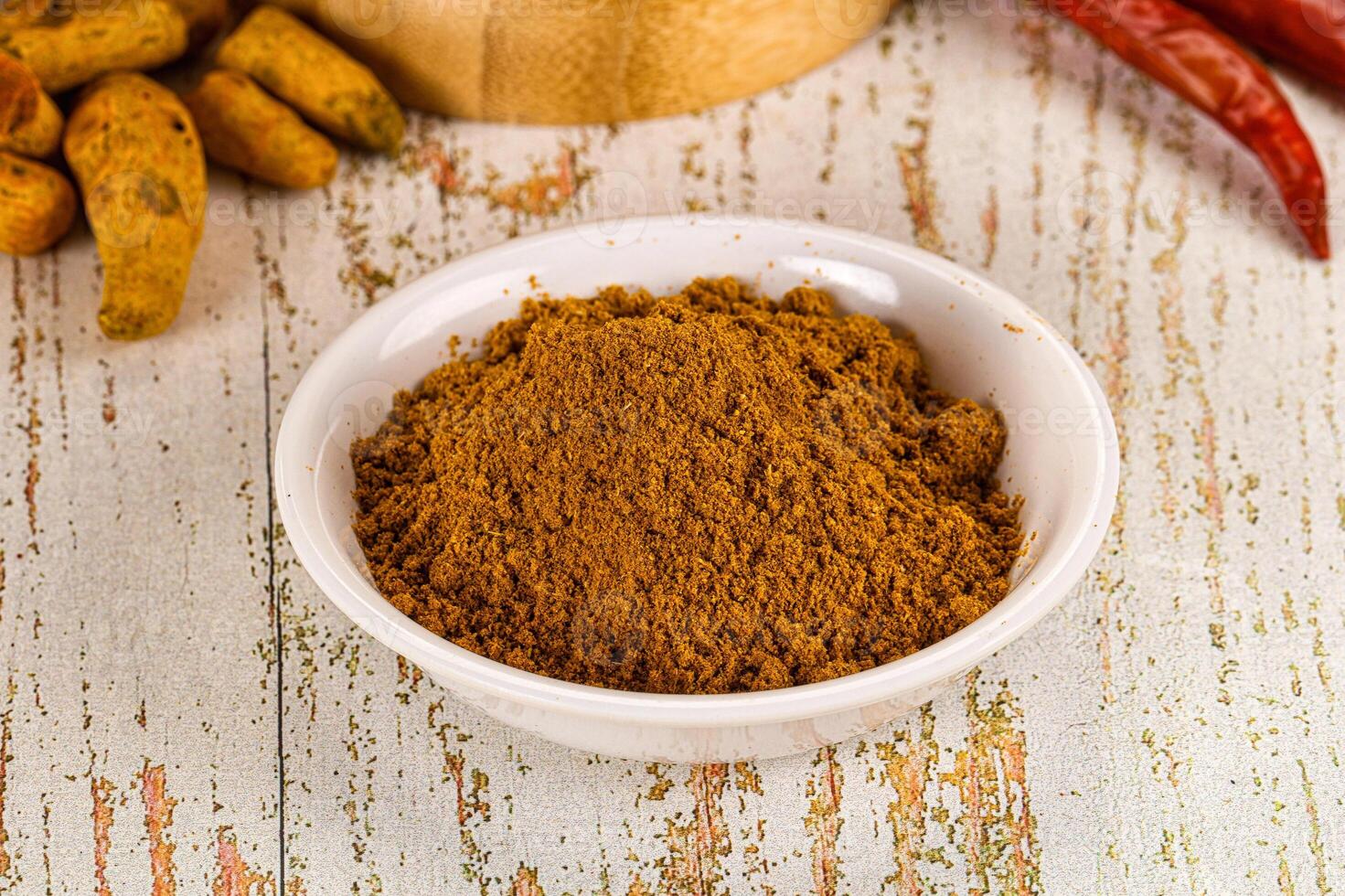 A bowl of curry powder next to a bowl of chili peppers photo