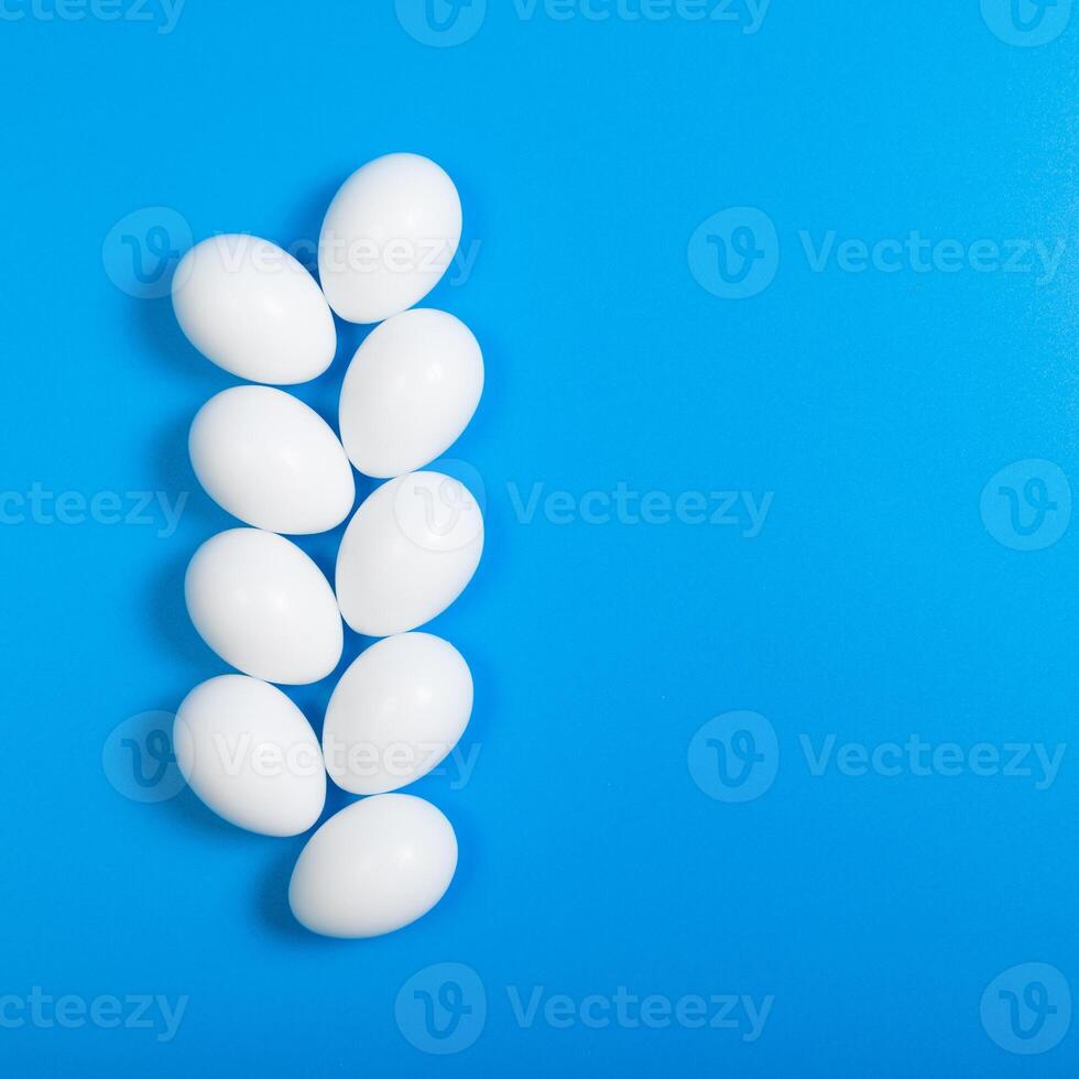 rows of eggs beautifully arranged on a blue background, top view, square format, space for text photo