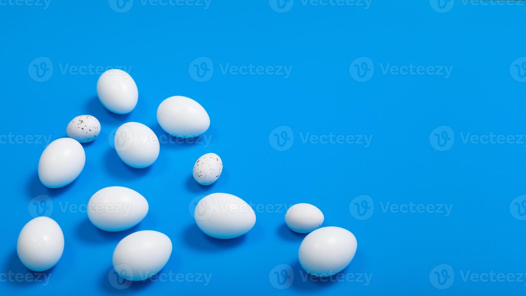 white eggs chaotically arranged on a blue background, horizontal format, space for text photo