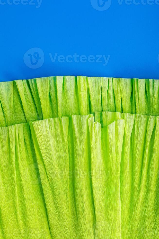 Brightly colored green crepe paper on a vivid blue backdrop. Vertical format ideal for cards, greetings, invitations, and banners. photo