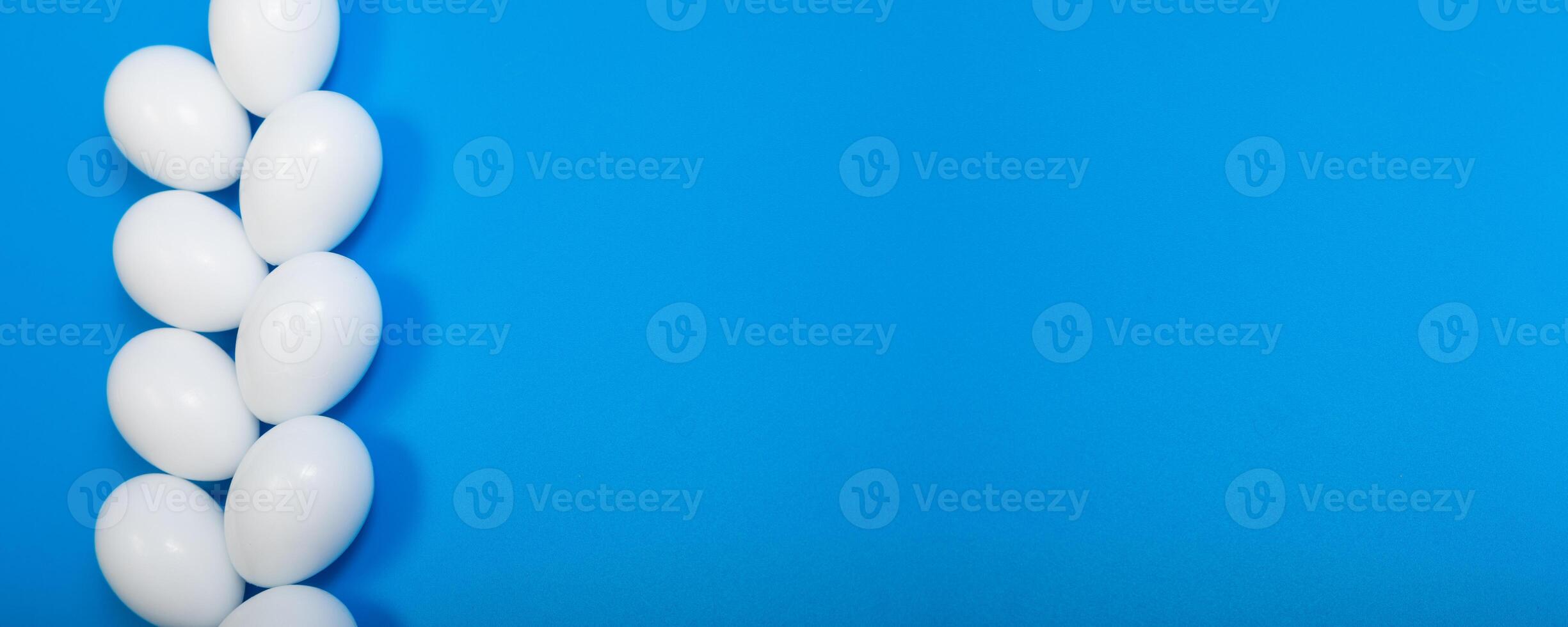 a row of eggs beautifully arranged on a blue background, top view, space for text photo
