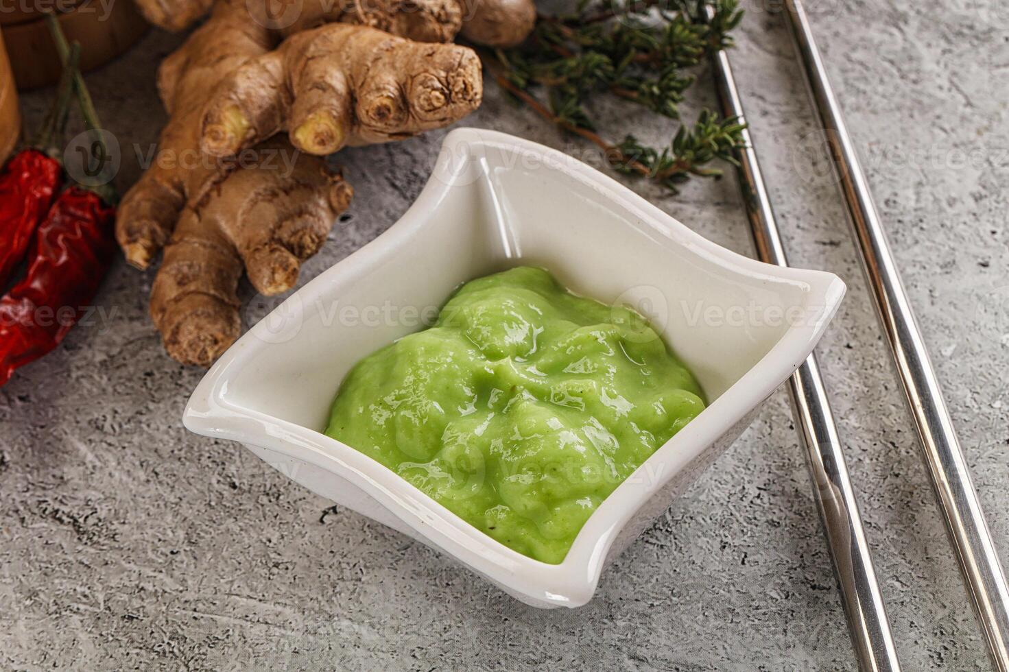 A bowl of green sauce next to a bowl of ginger photo