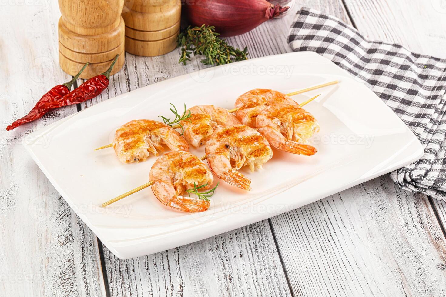 A plate with shrimp and vegetables on skewers photo
