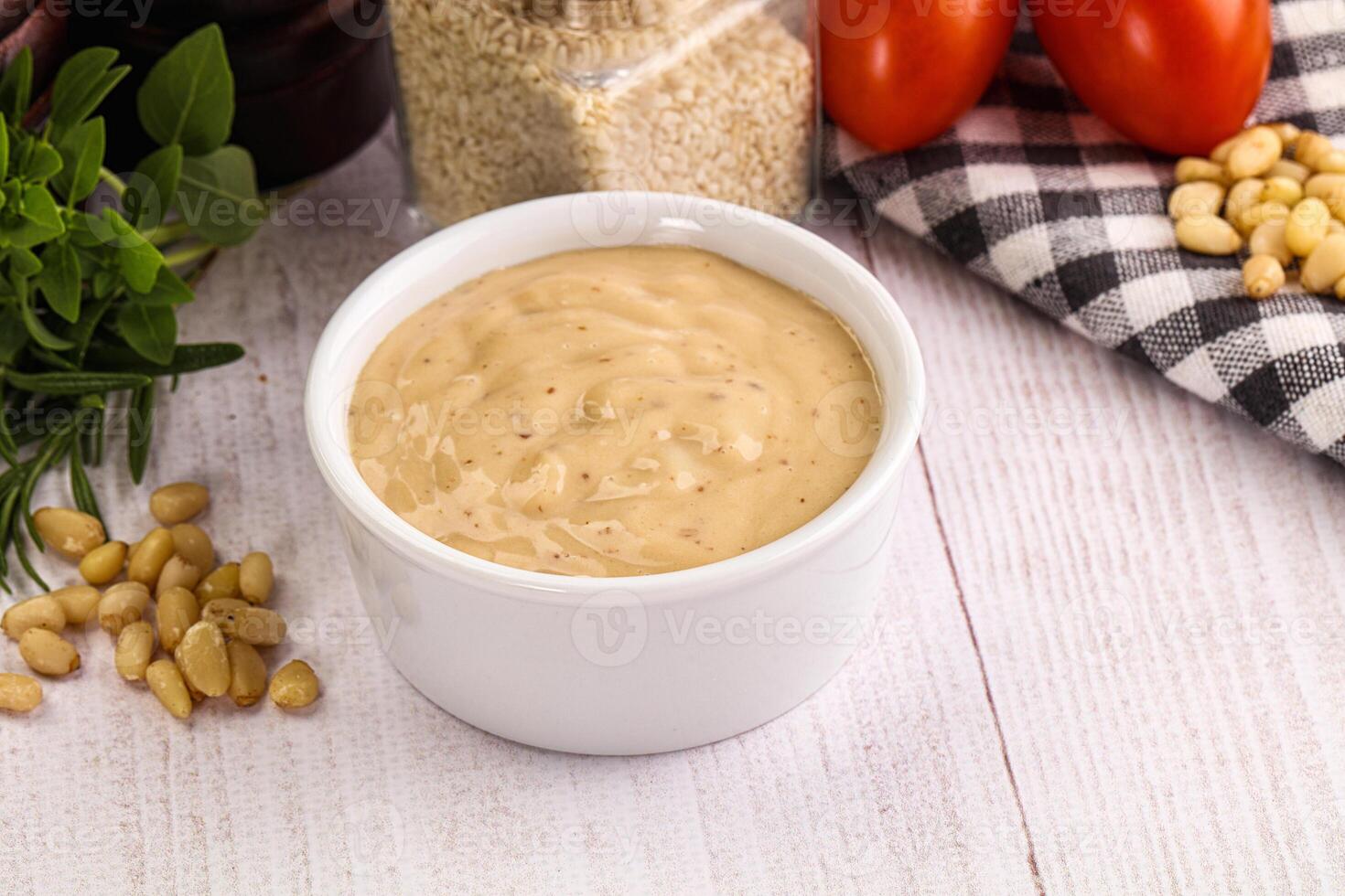 A bowl of peanut butter sauce on a wooden table photo