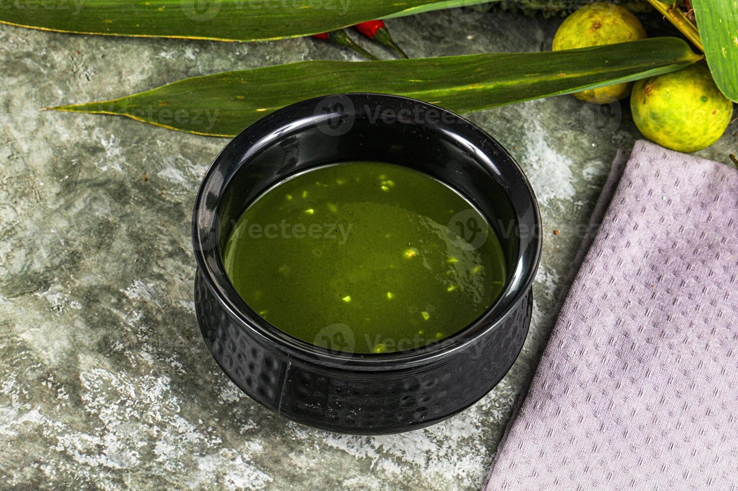 A cup of green liquid sitting on a table photo