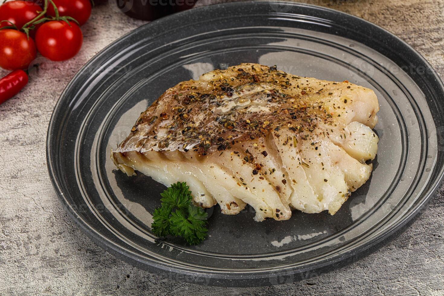 A piece of fish on a plate with tomatoes and herbs photo