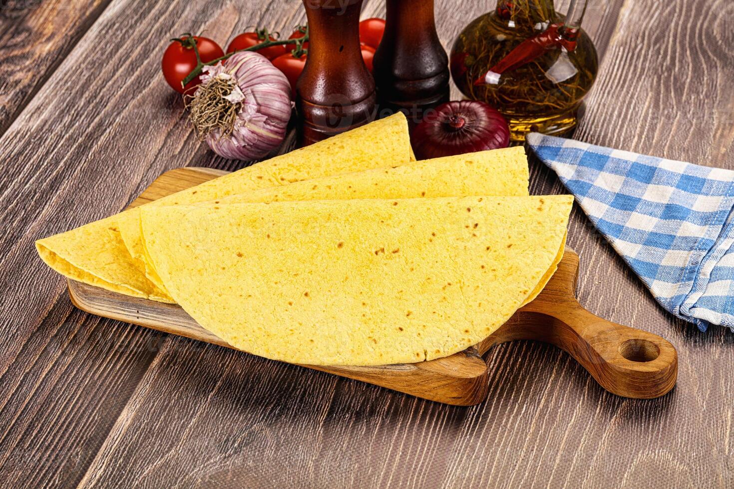 Three tortillas on a cutting board with tomatoes and spices photo