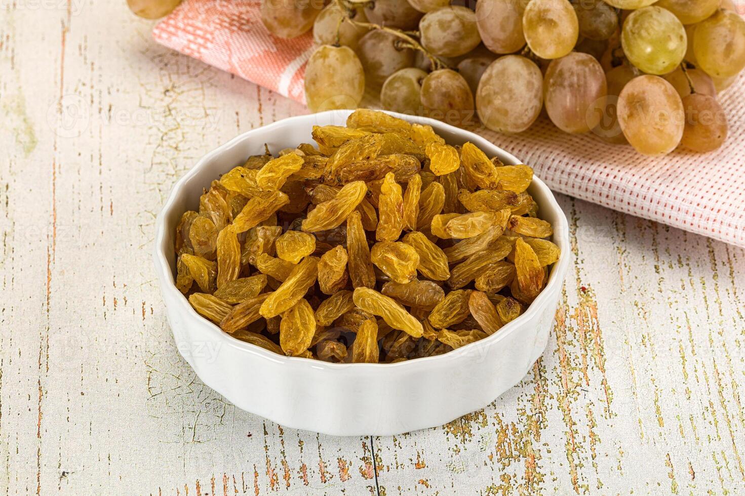 A bowl of raisins and a bunch of grapes photo