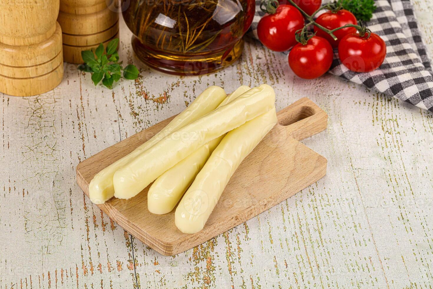 A wooden cutting board with some vegetables and a bottle of vinegar photo