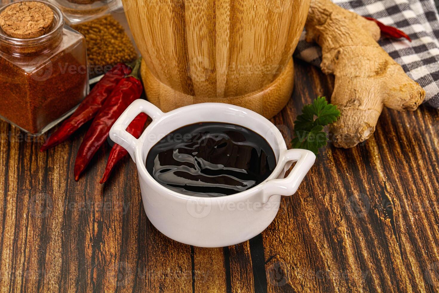 A cup of black liquid next to spices and ginger photo