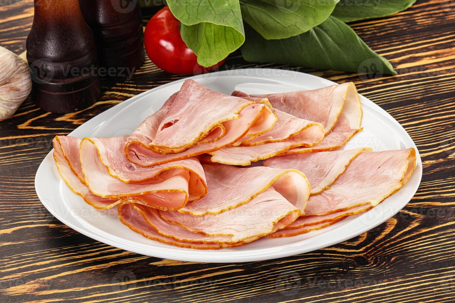 A plate of sliced ham on a wooden table photo