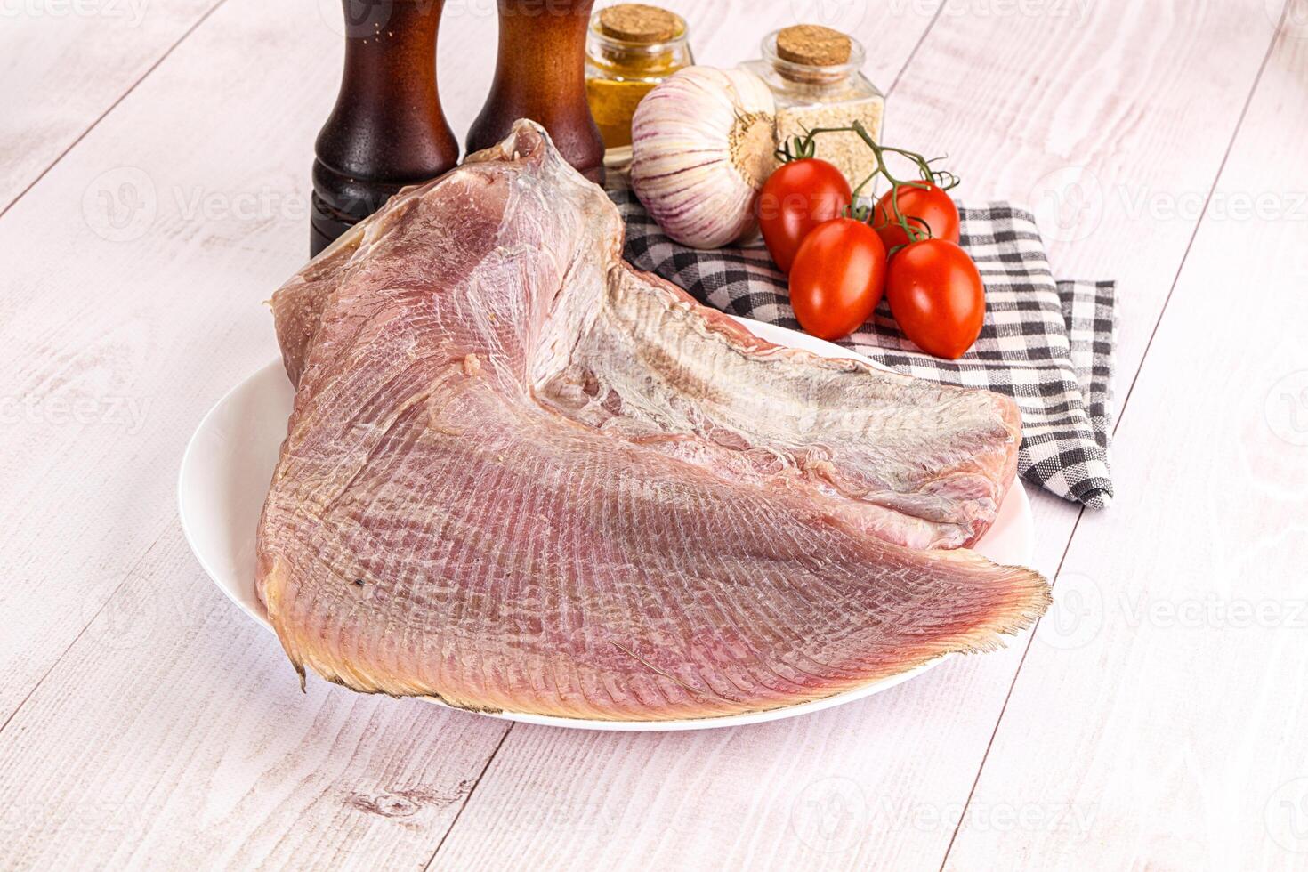 Raw fish on a plate with tomatoes and spices photo
