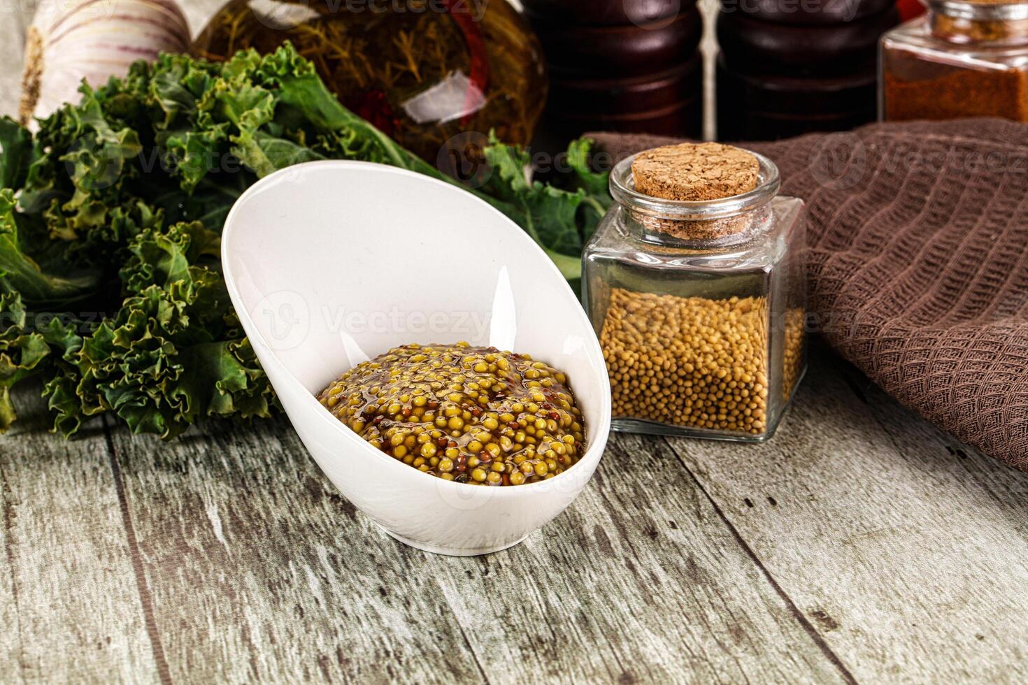 A bowl of mustard and a bowl of spices on a table photo