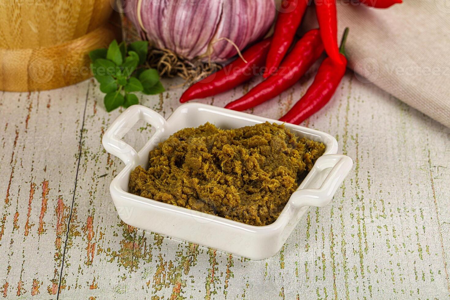 A bowl of green curry paste with spices and vegetables photo
