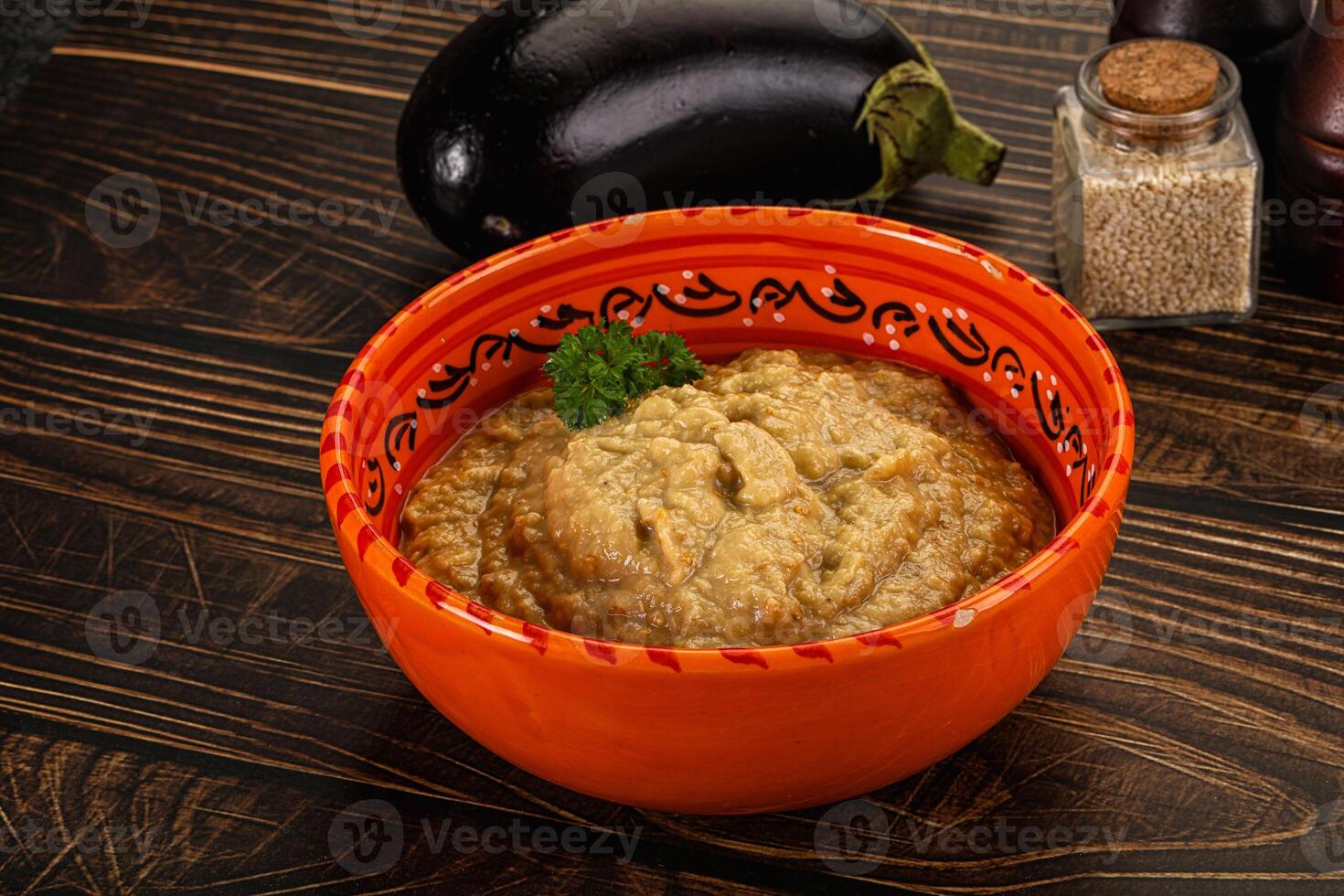 A bowl of hummus with a spoon and a pepper photo