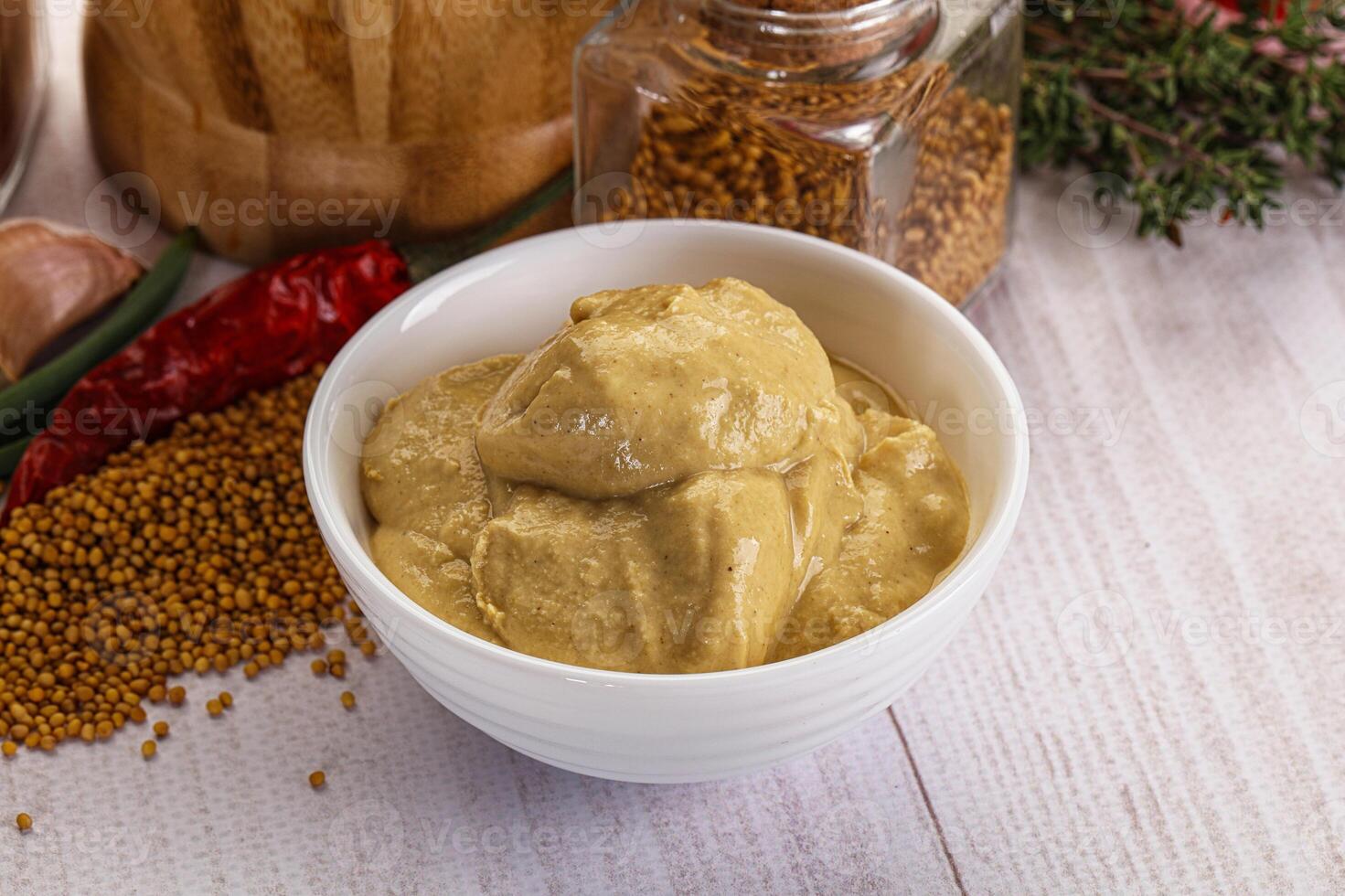 A bowl of mustard next to spices and other ingredients photo