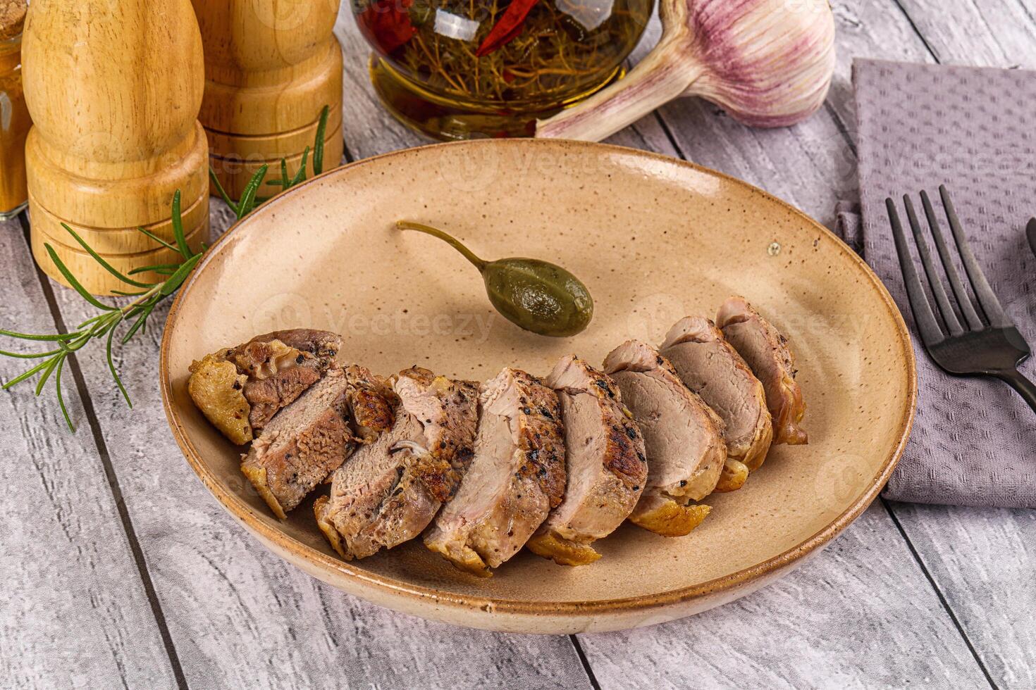 A plate of meat on a wooden table with a knife and fork photo