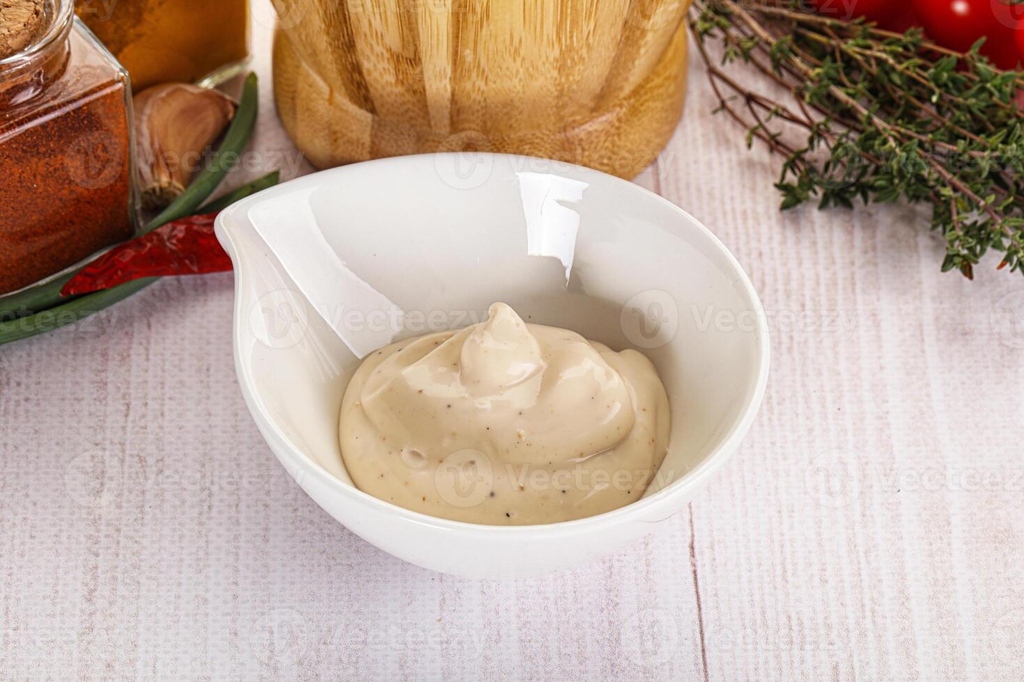 A bowl of dressing next to a bottle of mustard photo
