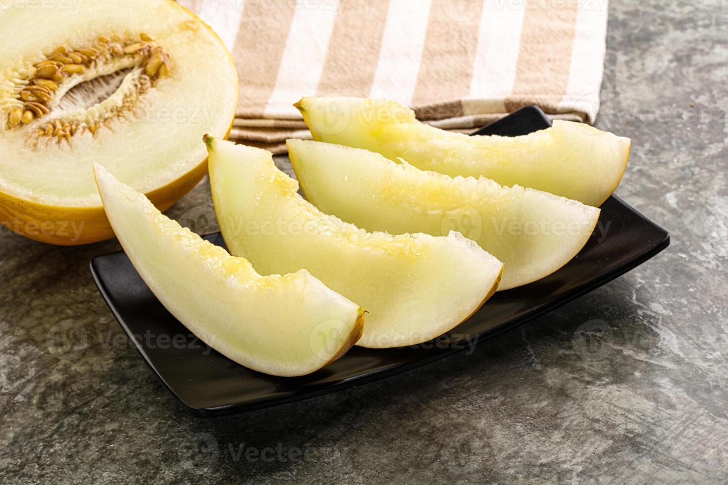 A melon on a plate with a knife and a knife photo