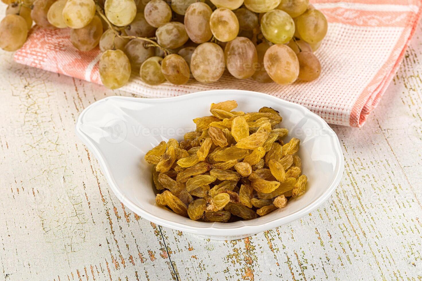 A bowl of raisins and a bowl of grapes photo