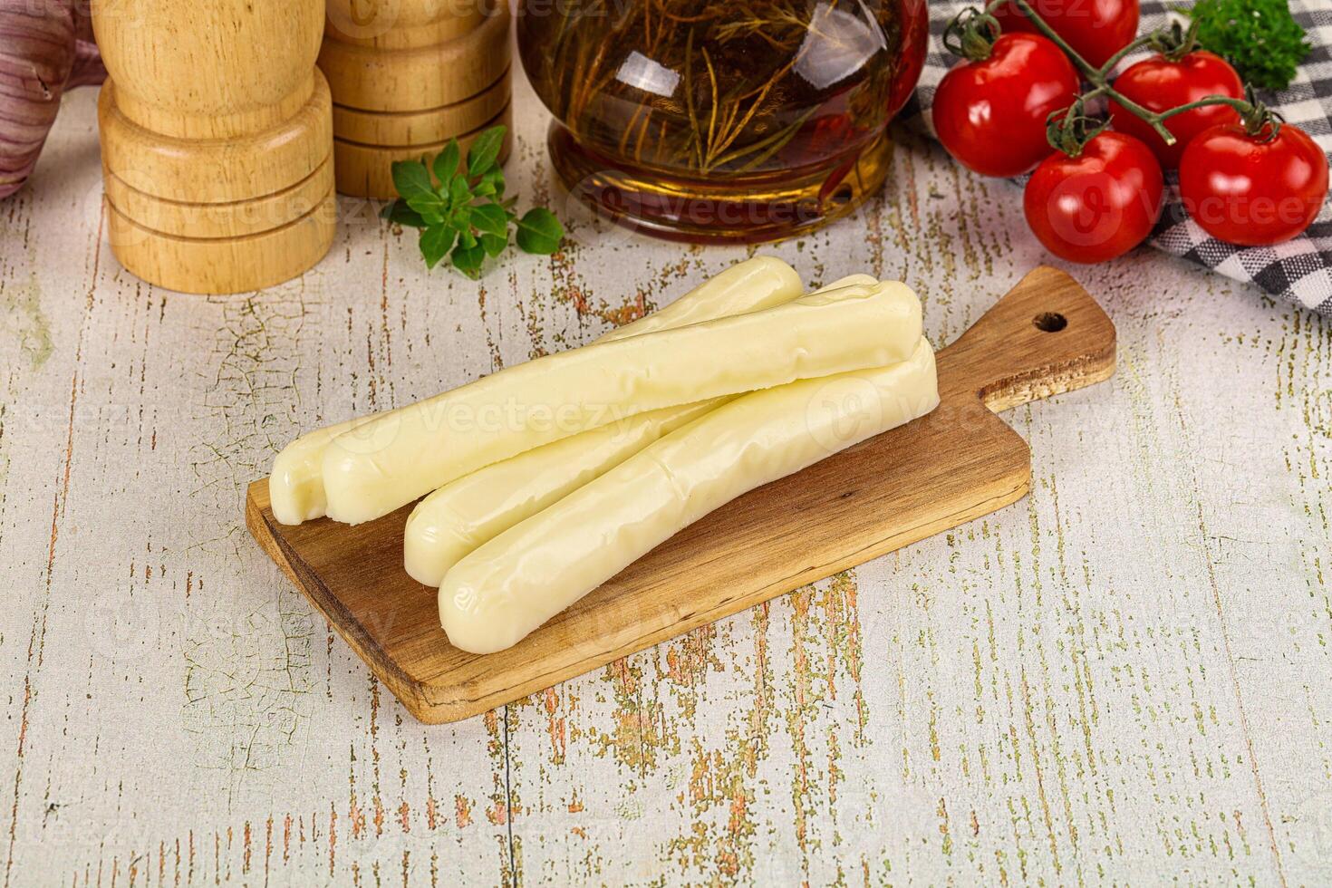 A wooden cutting board with cheese and other ingredients photo