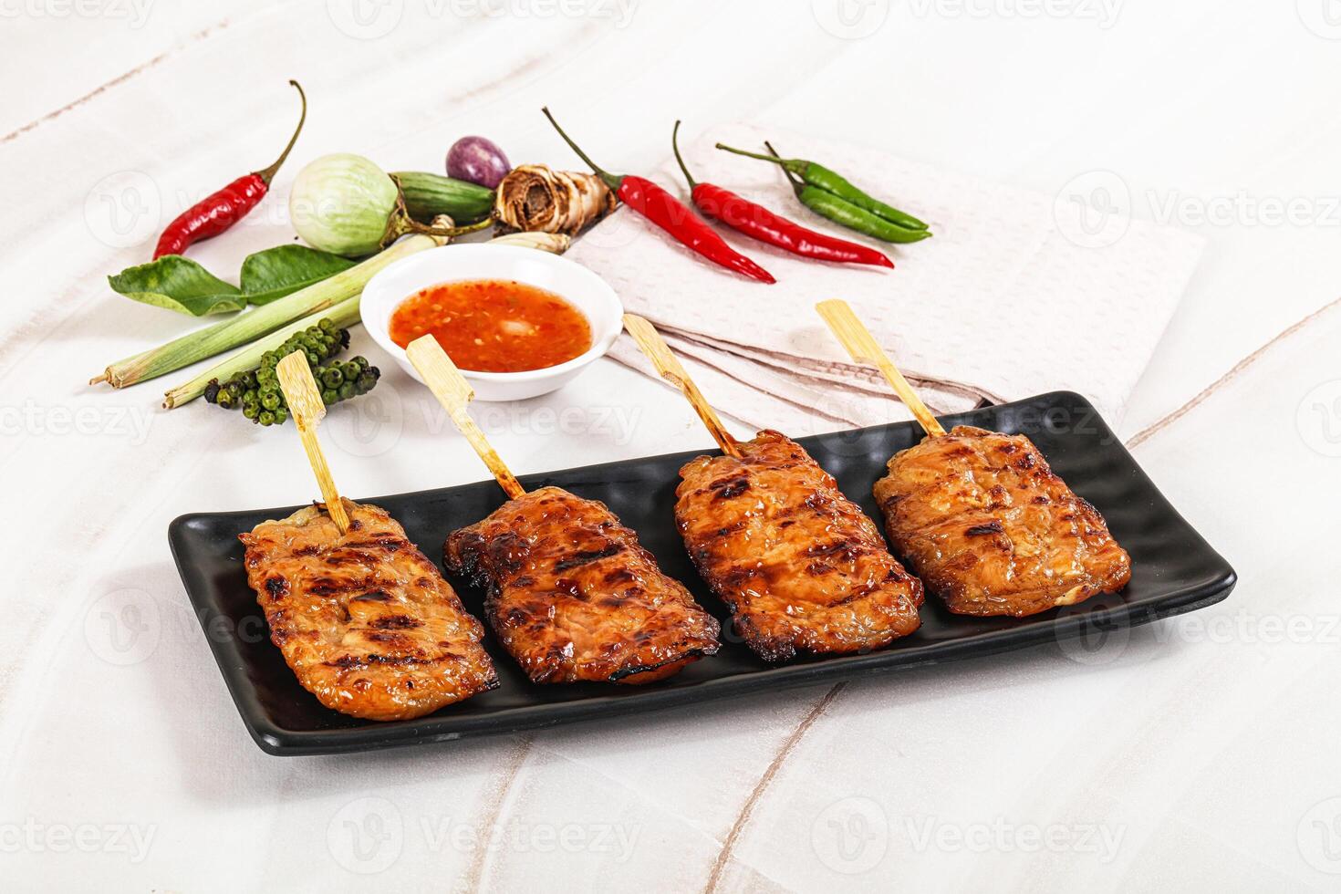 A plate with four skewers of meat on a black plate photo