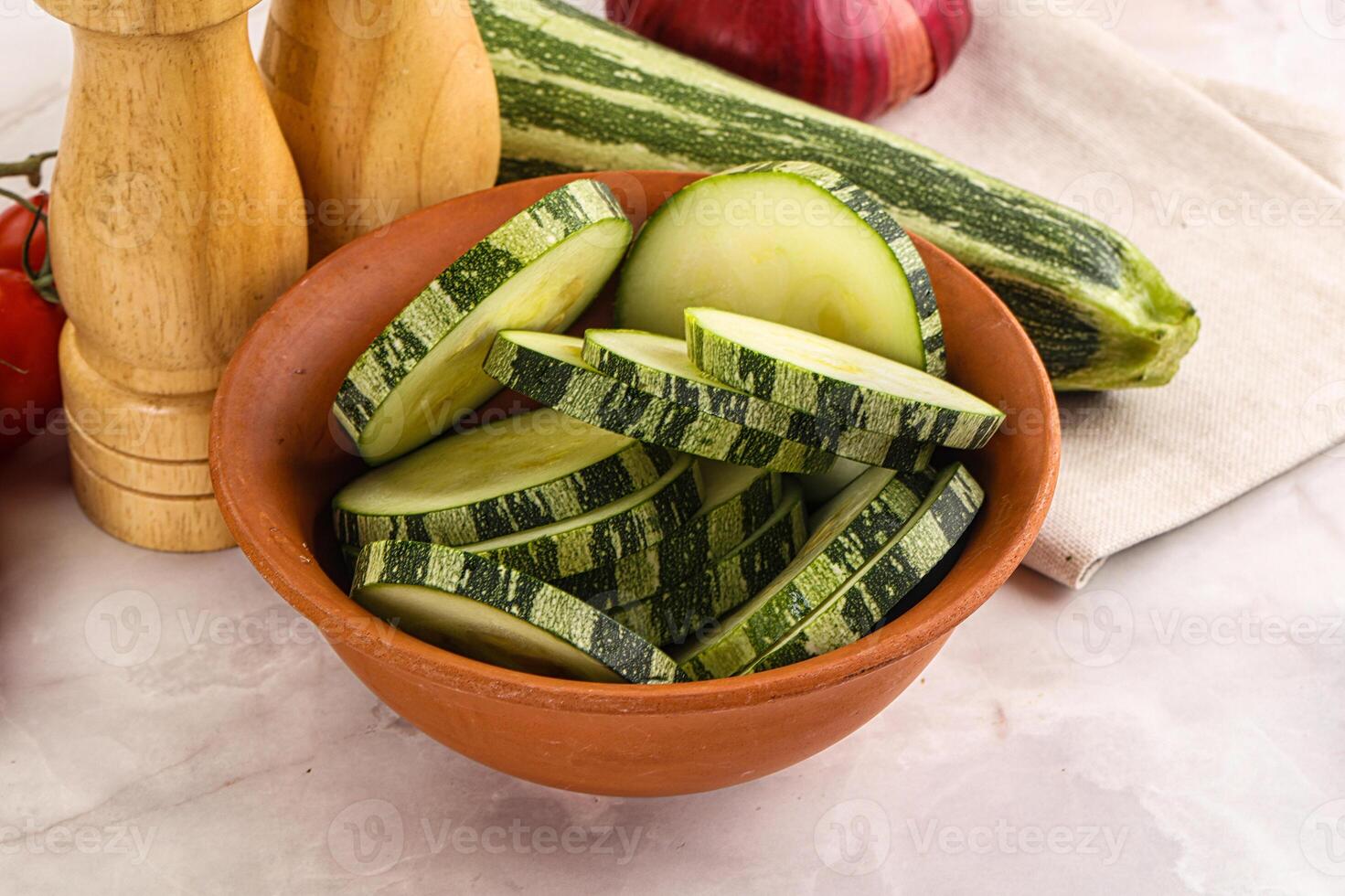 A bowl of sliced cucumbers and a wooden chopping board photo