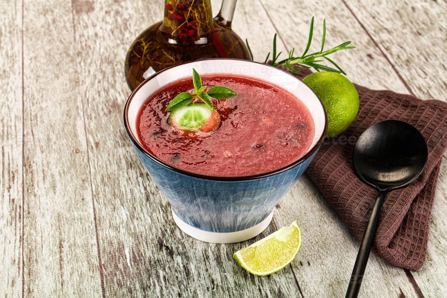 A bowl of red smoothie with a lime slice and a spoon photo