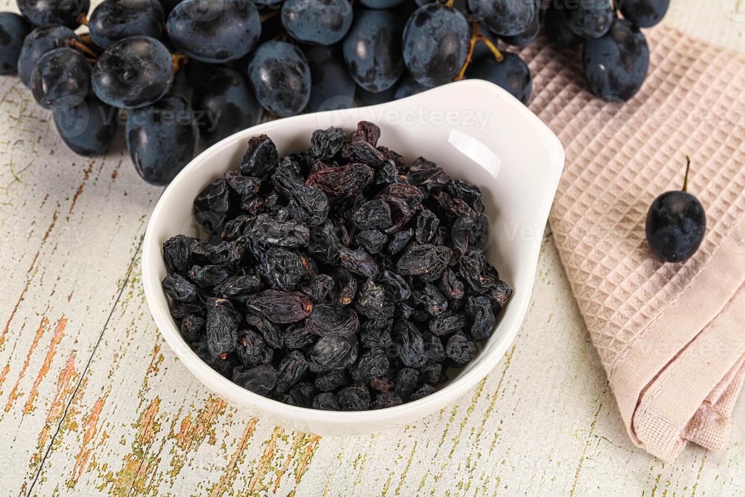 A bowl filled with black grapes and a napkin photo