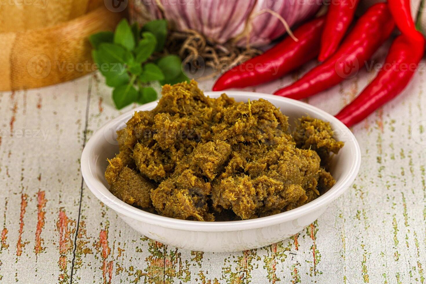 A bowl of curry with spices and red peppers photo