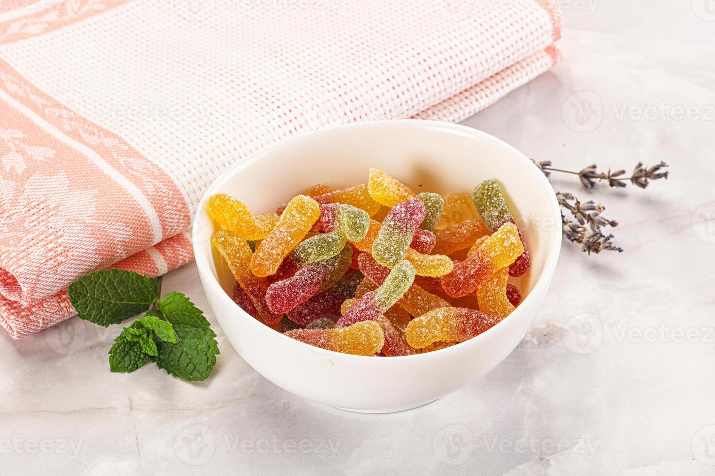 A bowl of gummy bears with a towel on the table photo