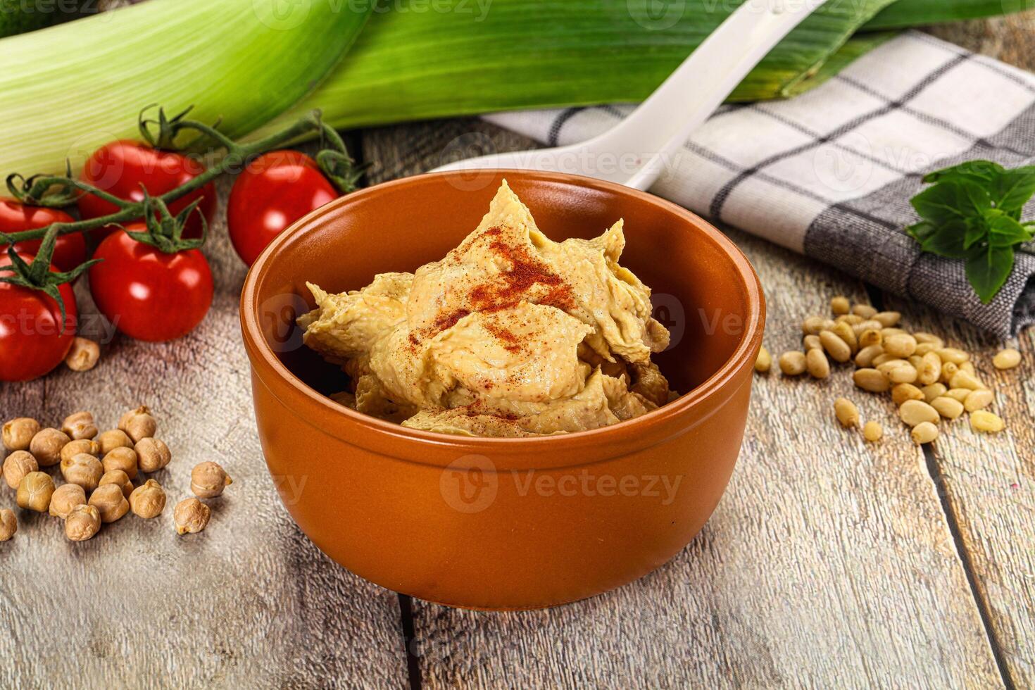 A bowl of hummus with vegetables and a spoon photo