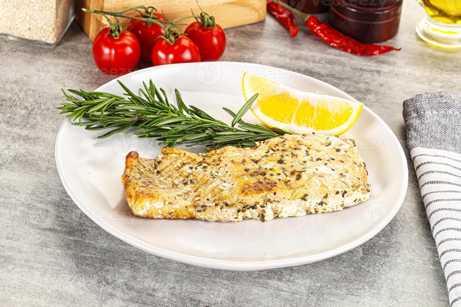 A piece of fish on a plate with lemon and herbs photo