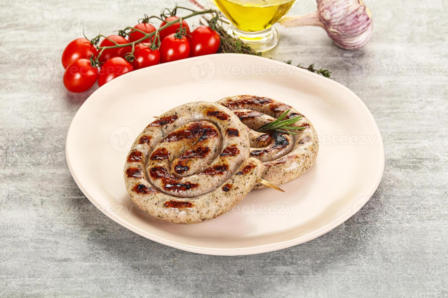 Two grilled sausages on a plate with tomatoes and garlic photo