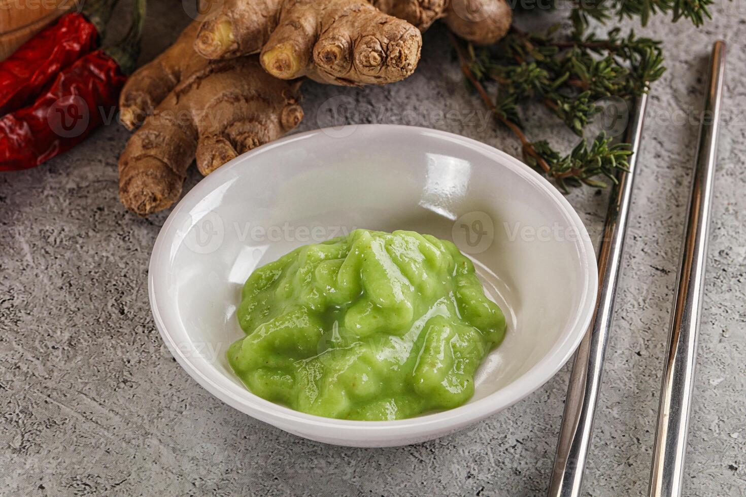 A bowl of green food with chopsticks and ginger photo