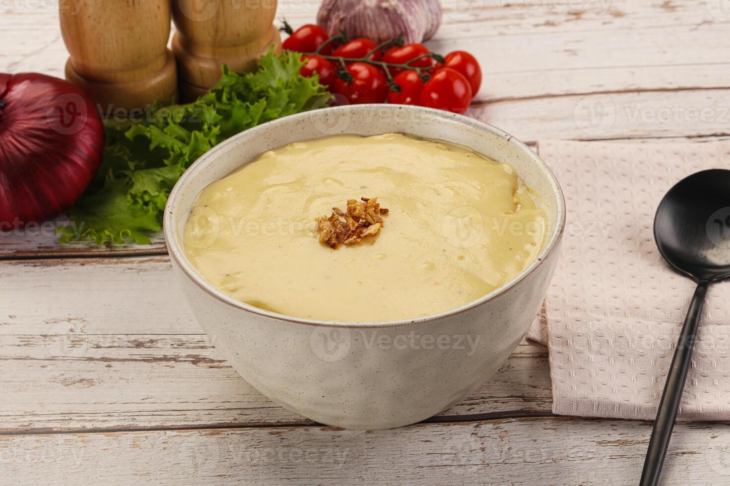A bowl of soup with a spoon and a knife photo