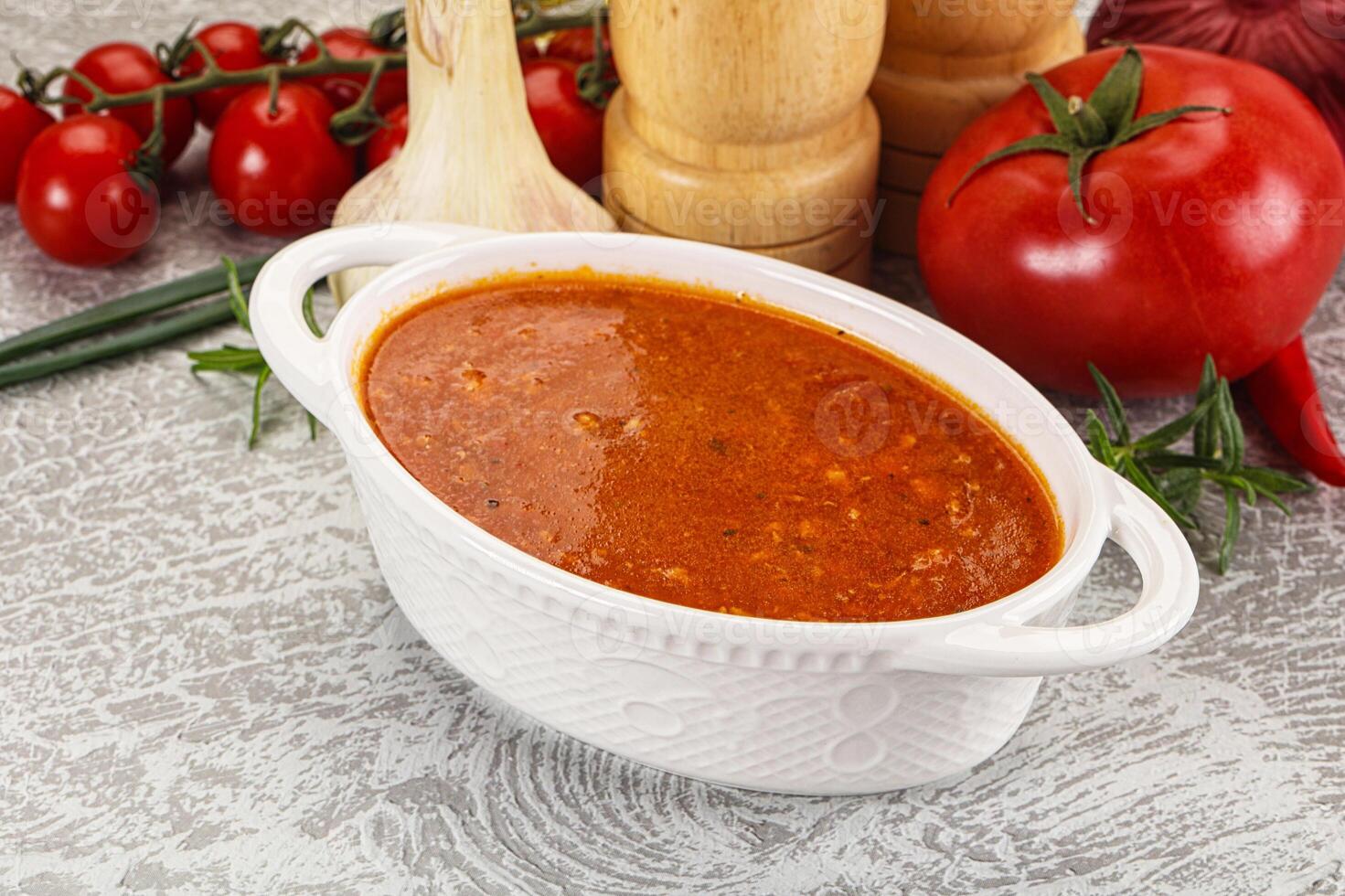 A bowl of tomato sauce next to a knife and a pepper photo