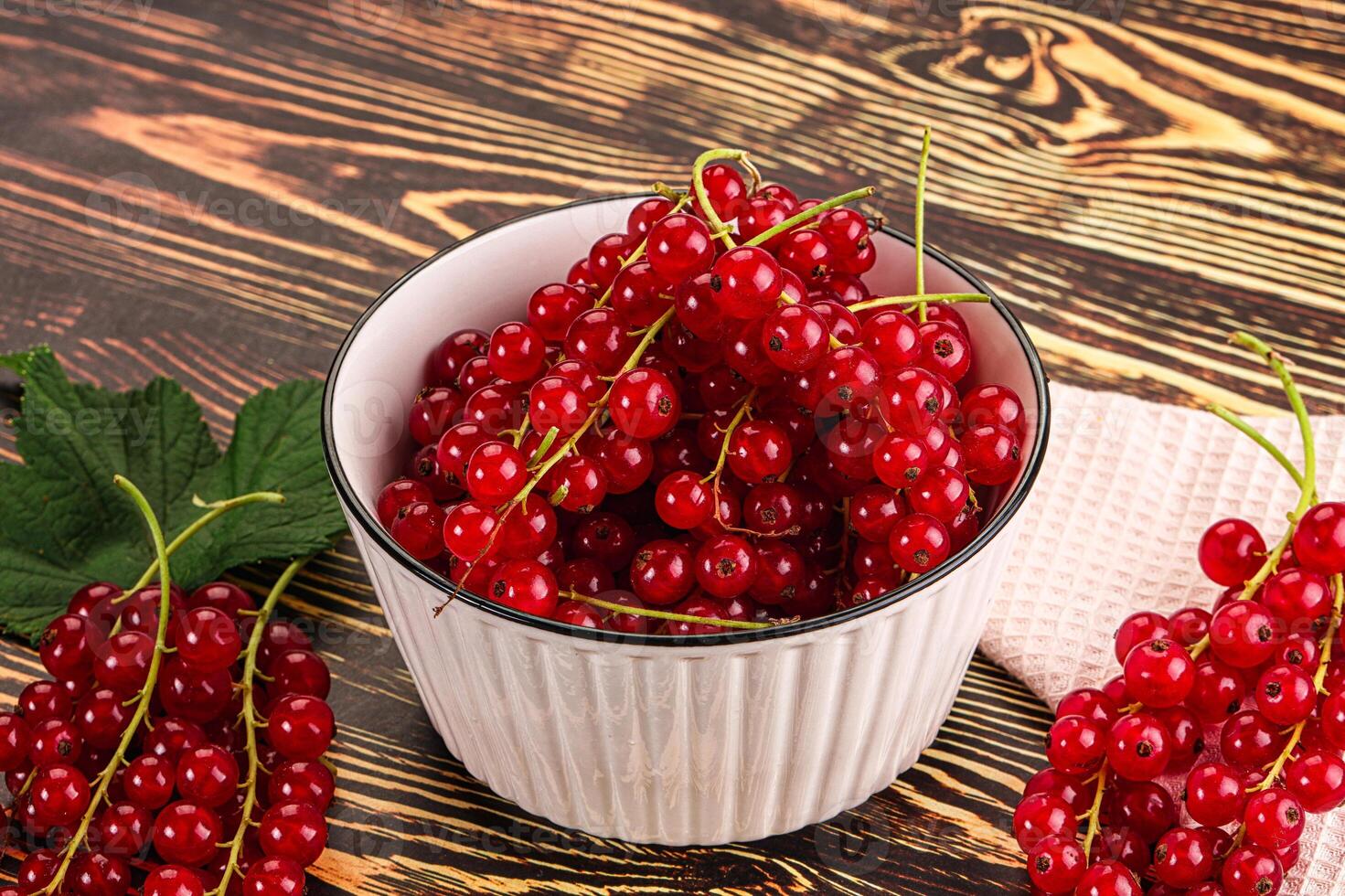 A bowl of red currants on a wooden table photo