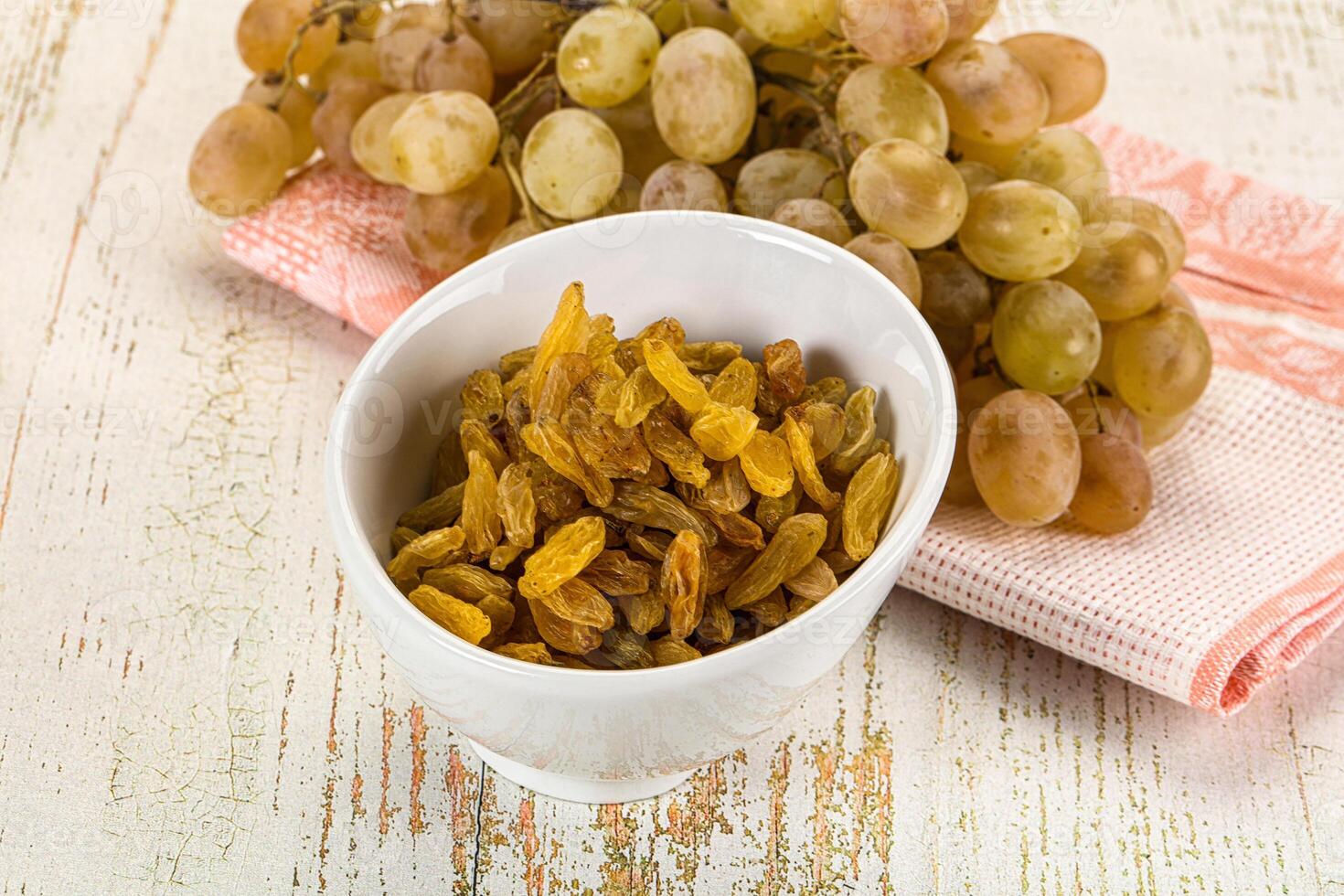 A bowl of dried fruit and a bunch of grapes photo
