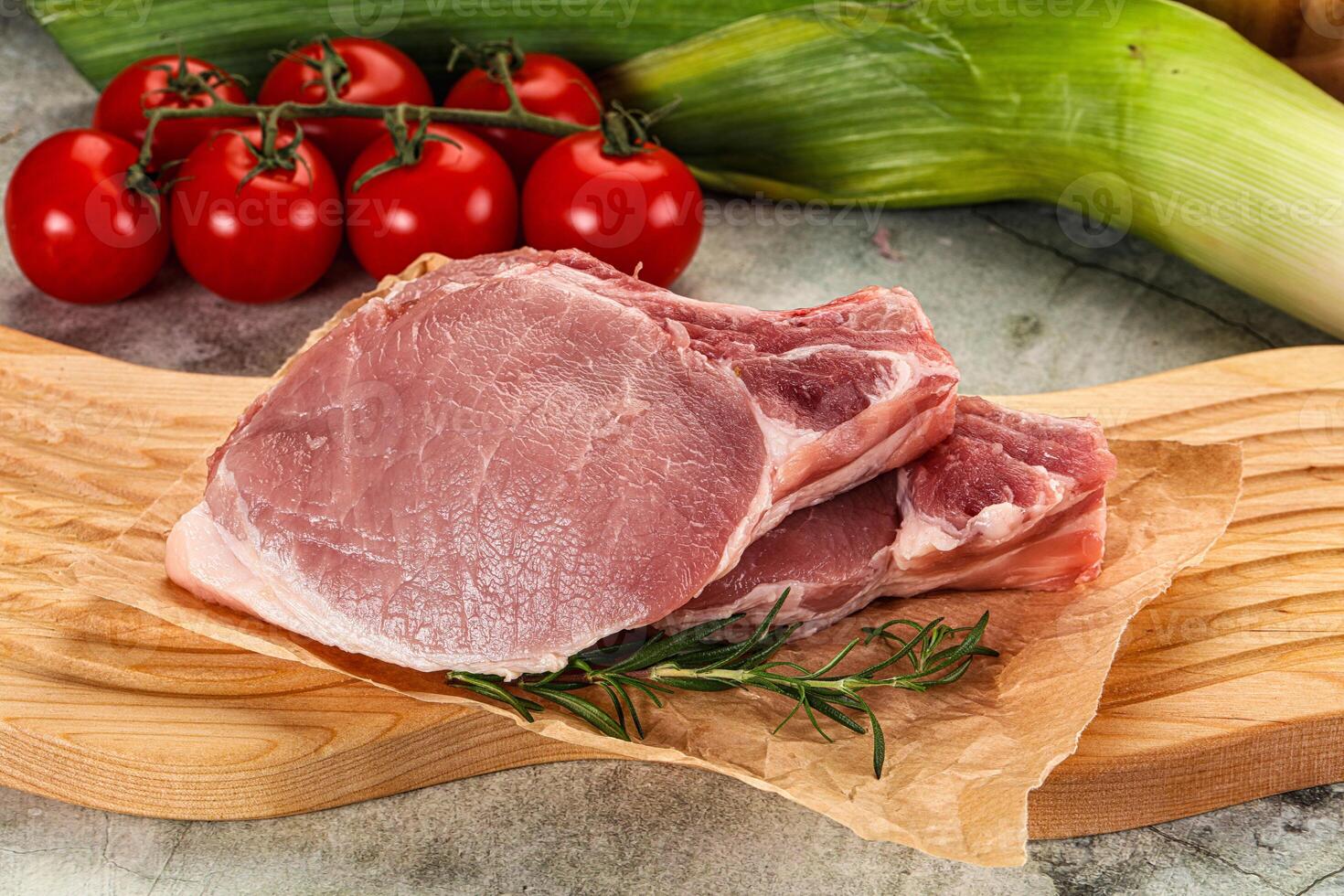 A piece of meat on a cutting board with tomatoes and vegetables photo