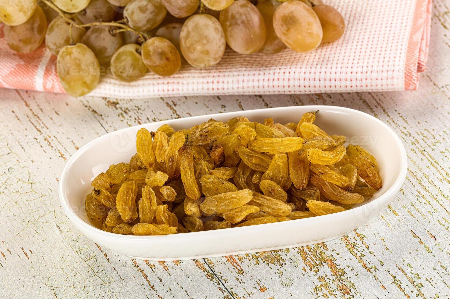 A bowl of raisins and a bowl of grapes photo