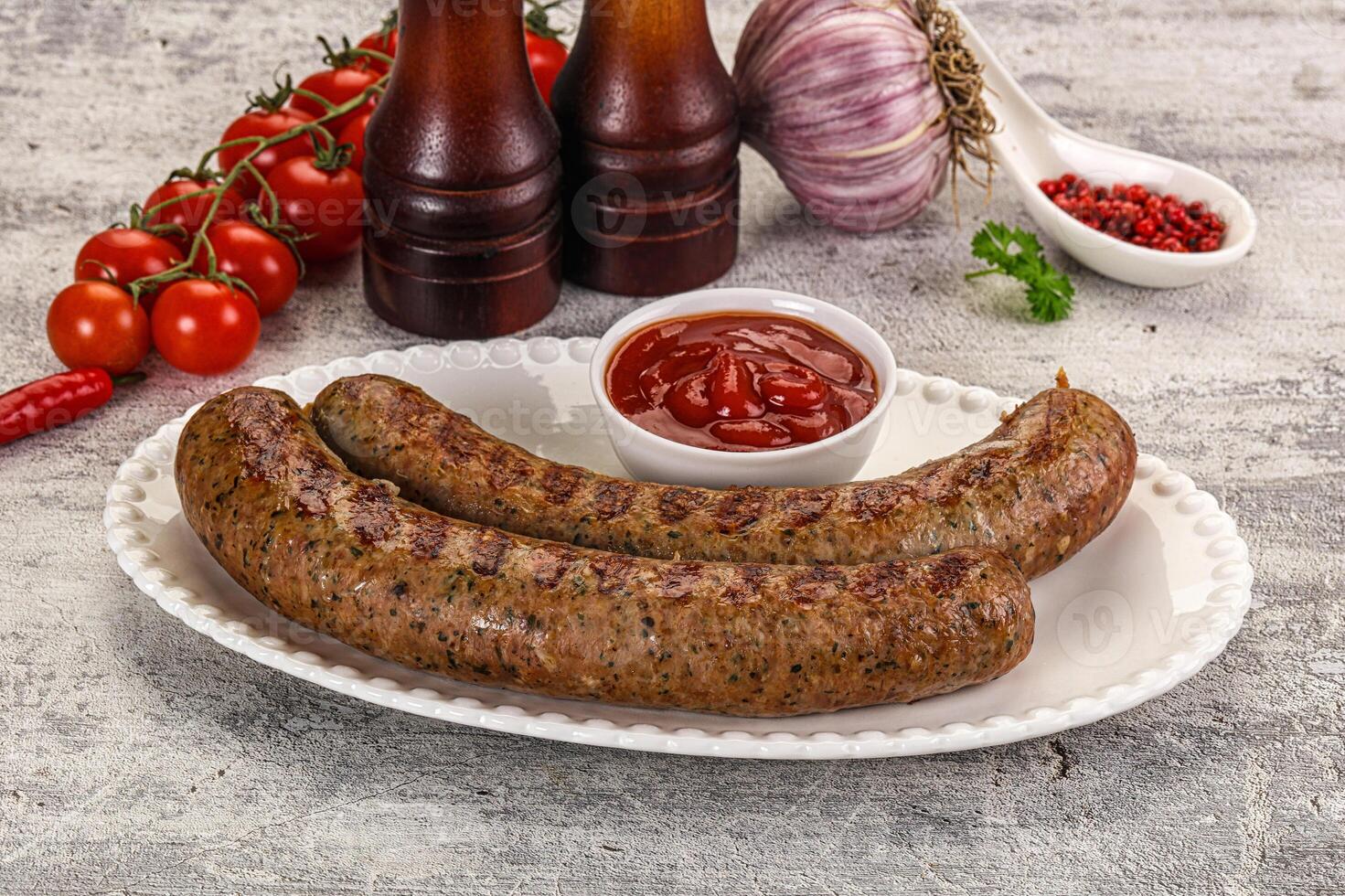 Two sausages on a plate with ketchup and tomatoes photo