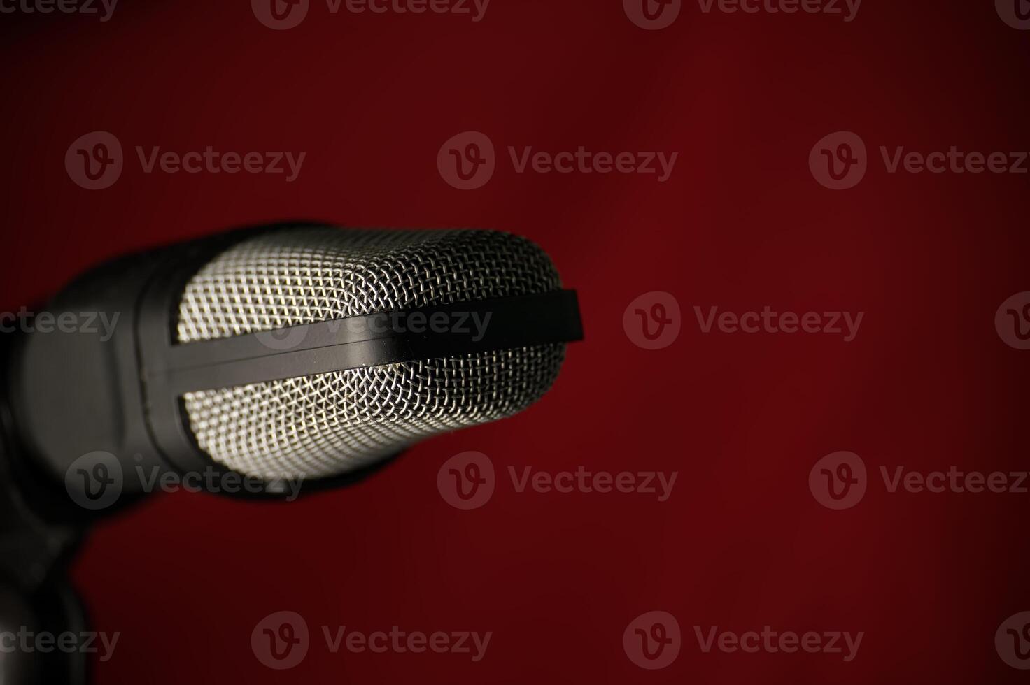 Closeup of a studio microphone against a dark red background photo