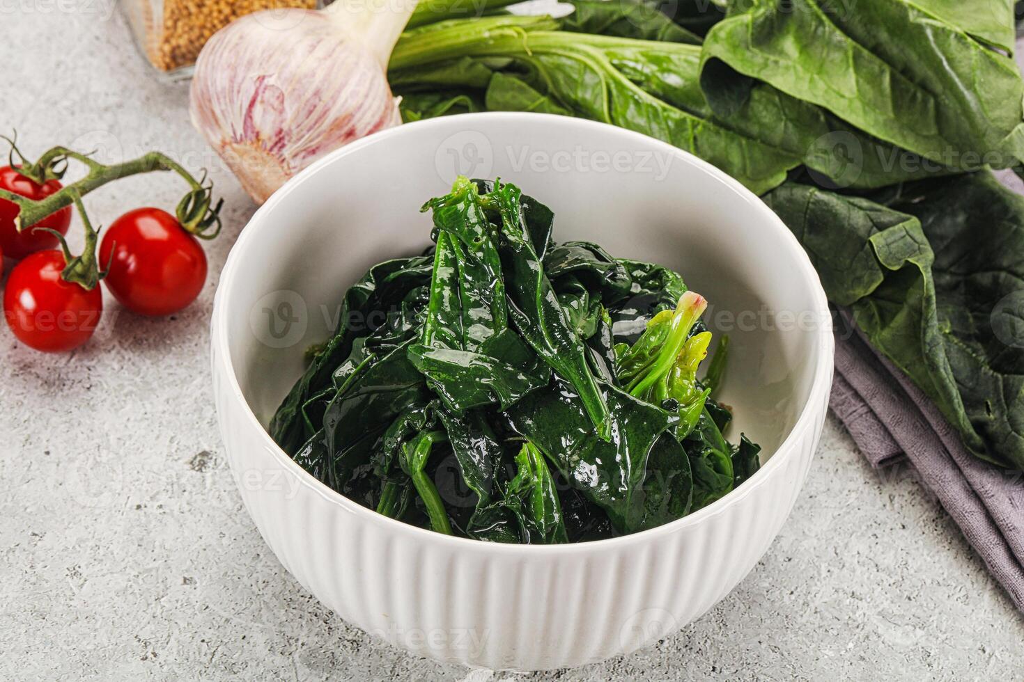 A bowl of spinach with tomatoes and garlic photo