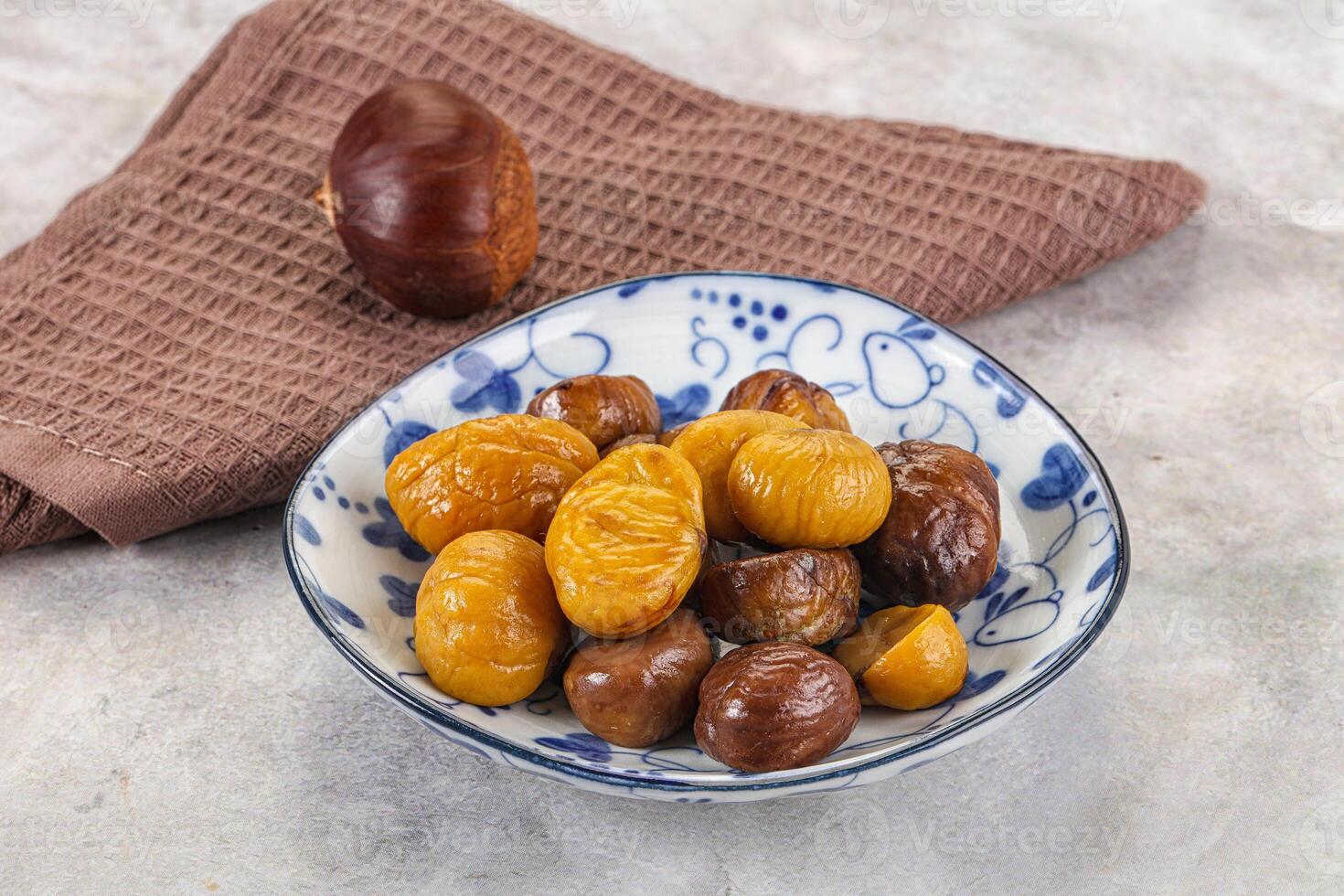 A bowl of dried chestnuts and a towel on a table photo